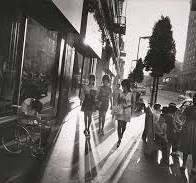 A photo centred on three women walking down the street with everything in the background telling a story.(Captured by Garry Winogrand)